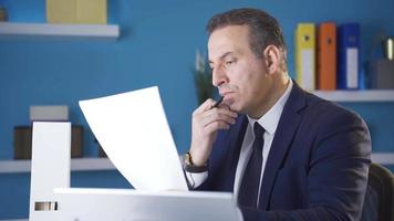 Serious and focused businessman analyzing graphs and data in office. Focused serious businessman analyzing graphs and data in office. video
