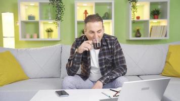 el contento hombre con un positivo negocio vida es pacífico y relajado. contento y relajado hombre acerca de trabajar, Bebiendo su café a hogar a ordenador portátil. video