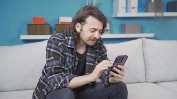 le homme à la recherche à le téléphone est ennuyé et malheureux. le homme à la recherche à le téléphone à Accueil est ennuyé et malheureux. léger pleurs. video