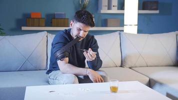 The young man who is fond of drugs is sticking a needle into his vein at home.  The young man who started drugs uses heroin at home and hurts. video