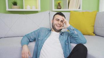 Young man in happy thoughts at home. Dreams. Young man sitting alone at home thinking about happy moments and smiling video