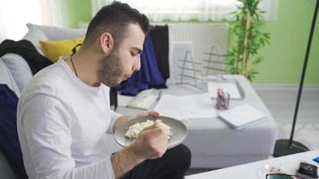 Single young man living in dirty and messy house eating. The young man living in the dirty and untidy house is content with himself. video