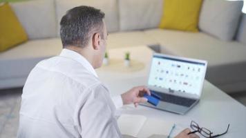 Man shopping online using laptop and credit card. The man who orders from e-commerce follows from the computer and the shopping is completed. video