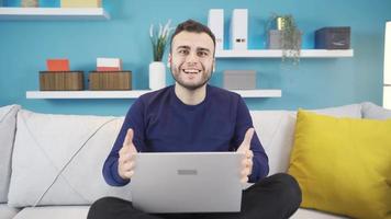 ritratto di contento giovane uomo ricevente bene notizia. giovane uomo utilizzando il computer portatile a casa gioia e contento a bene notizia. video