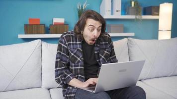 hombre mirando a ordenador portátil es sorprendido y contento. el hombre utilizando el computadora es sorprendido y alegría a qué sucedió. muy contento. video
