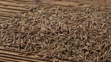 Aromatic cumin dry seeds texture on a wooden table video