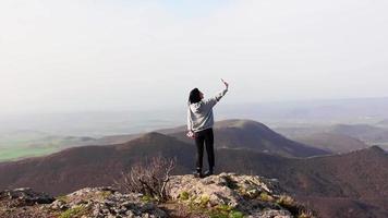 Zoom dans vue Jeune attrayant brunette prend selfie intelligent téléphone avec scénique paysage montagnes Contexte. video