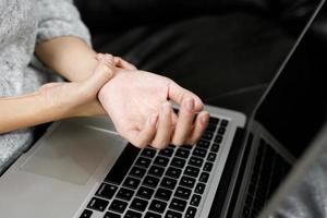 mano dolor mujer ella es trabajando en el computadora foto