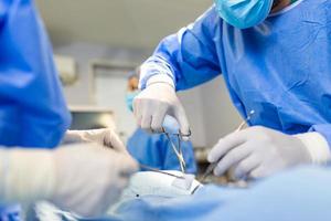 equipo de médicos profesionales que realizan operaciones en la sala de cirugía. equipo médico que realiza una operación quirúrgica en un quirófano moderno y luminoso foto