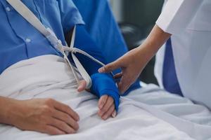 Injured patient showing doctor broken wrist and arm with bandage in hospital office or emergency room. Sprain, stress fracture or repetitive strain injury in hand. Nurse helping customer. First aid. photo