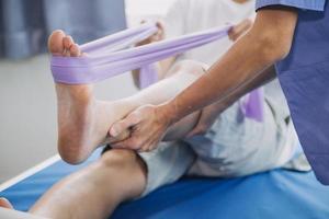 médico o fisioterapeuta trabajando examinando tratando lesionado brazo de atleta masculino paciente, extensión y ejercicio, haciendo el rehabilitación terapia dolor en clínica. foto