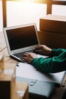 SME entrepreneur Small business entrepreneurs Online selling ideas,Happy Young Asian business owner work on computer and a boxs at home,delivery SME procurement package box deliver to customers, photo