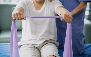 Doctor or Physiotherapist working examining treating injured arm of athlete male patient, stretching and exercise, Doing the Rehabilitation therapy pain in clinic. photo