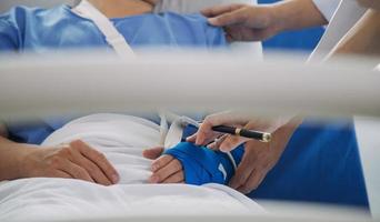 Injured patient showing doctor broken wrist and arm with bandage in hospital office or emergency room. Sprain, stress fracture or repetitive strain injury in hand. Nurse helping customer. First aid. photo