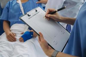 Injured patient showing doctor broken wrist and arm with bandage in hospital office or emergency room. Sprain, stress fracture or repetitive strain injury in hand. Nurse helping customer. First aid. photo