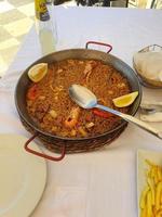 caliente Español paella con Mariscos y langostinos y un cuchara foto