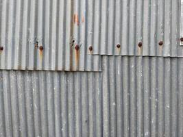 Closeup old and rusty corrugated zinc sheet wall, grunge background metal texture photo