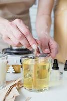 closeup of woman setting the wooden wick into handmade candle photo