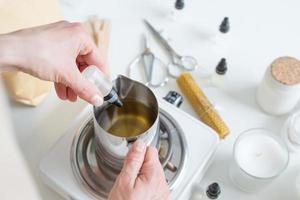 Woman making decorative aroma candle adding aroma, closeup photo