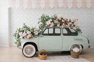 Retro mint car decorated with flowers in the photo zone in a romantic style for Spring Day or St. Valentine