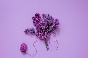 Bouquet of lilac, tied with a string on a lilac background. Flat lay holiday card photo