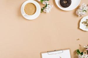 Spring flat lay with apple flowers. Woman's workplace. Tea break with Donut. Copy space photo