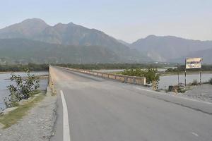 A narrow bridge road on Sindhu River in Kashmir with warning sign photo