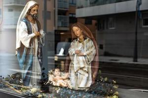 large figures of saints from the nativity scene for Christmas, close to the reflection of the city in the glass photo