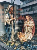 sculptures from the Christmas nativity scene behind the glass reflecting the city photo