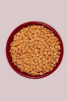 Red lentil in bowl isolated on pink background. Top view photo