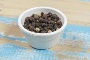 bowl with ground black pepper on blue rustic wooden table photo