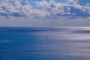 calm blue seaside landscape with water and sky and sailboats photo