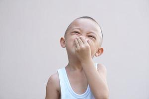 Asian boy covering his nose from the bad smell with his hand photo