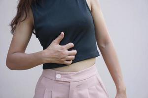 asiático mujer teniendo un que produce picor estómago foto