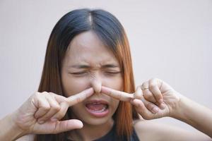 Asian woman covering her nose from bad smell with her hands photo