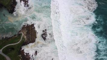 von oben nach unten Aussicht von Rau Ozean mit schaumig Wellen abstürzen Über Klippen im Caion Strand im Koruna, Spanien. Antenne Drohne Schuss video