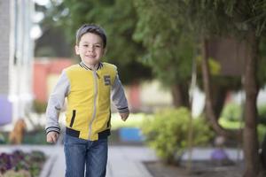 A smiling preschooler walks along the street. A merry child in the background of the city. photo