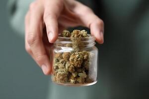 hand hold cannabis dry buds in glass jar, marijuana legalization photo