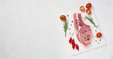 Raw pork tenderloin on the bone and spices on a white background. Portion for lunch and dinner, top view photo