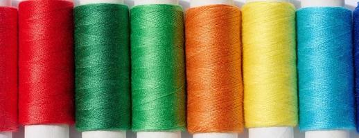 Multicolored spools of sewing threads on a white background, top view photo