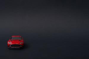 A photo of a red toy car on isolated black background, after some edits.