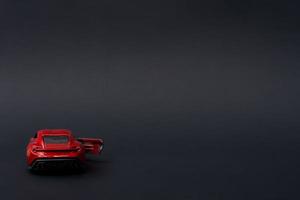 A photo of a red toy car on isolated black background, after some edits.