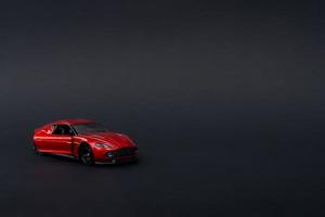 A photo of a red toy car on isolated black background, after some edits.