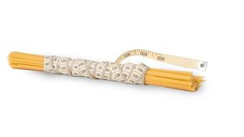manojo de crudo espaguetis atado con un medición cinta en un blanco antecedentes foto