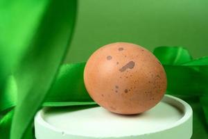 Easter eggs on a white podium with a green ribbon on a green background photo