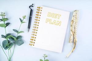 Notebook with pen and measuring tape on white background, diet and health plan concept photo