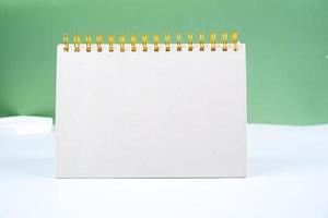 blanco blanco espiral bloc en un verde antecedentes. cuaderno con espacio para tu texto, Listo para tu mensaje. foto