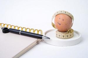 Chicken egg and measuring tape and pen on white background. Dieting concept photo