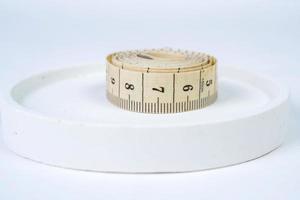 Measuring tape on a white podium on a white background. Selective focus and shallow depth of field photo