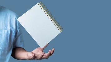 Blank notepad hovering over businessman's hand on light blue background, copy space for your text photo